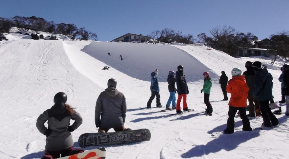 Snowboarders at the half-pipe.